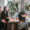 Four people are sitting around a table, engaged in a discussion. A plant is in the background. Voir les images du produit
