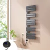 A modern electric towel radiator mounted on a wall next to a window with plants. Náhled obrázku produktu
