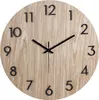 A close-up view of a round, wooden wall clock with black numbers and hands. Anteprima dell’immagine prodotto