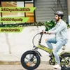 A man riding a green electric bicycle on a street. Produktbild-Vorschau