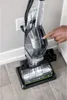 A hand is pressing a button on a BISSELL CrossWave Hydrosteam PET Select multi-surface cleaner. Voir les images du produit