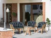 Outdoor patio furniture set with cushions and a table, placed on a patio in front of a house with large windows. Náhľad obrázku produktu