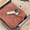 A lint remover is placed on folded clothes inside a suitcase. Náhled obrázku produktu