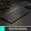 A minimalist wireless keyboard with illuminated keys is placed on a wooden desk, with a computer mouse and some papers in the background. Anteprima dell’immagine prodotto