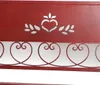 A close-up of a red metal garden bench with heart-shaped scrollwork. Produktbild-Vorschau