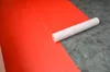 A roll of white protective fleece lies on a surface divided between red and gray sections. Produktbild-Vorschau
