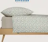 A close-up view of a bed with a pillow and fitted sheet, both featuring a small floral pattern. The bed frame is visible at the bottom. Produktbild-Vorschau