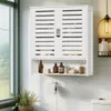 A white bathroom cabinet mounted on a tiled wall, with items on the open shelf below. Podgląd zdjęcia produktu