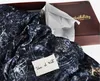 A dark, patterned fabric is laid out in a box, with a small note placed on it. A box with text is visible in the background. Anteprima dell’immagine prodotto