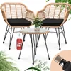 A rattan-look balcony set with two chairs and a small table, featuring black cushions and a glass tabletop. A small potted plant sits on the table. A red tag with "2+1 SET" is attached to the table. Produktbild-Vorschau