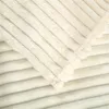 A close-up view of a cream-colored ribbed blanket. Podgląd zdjęcia produktu