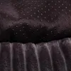 A close-up view of the bottom of a dog bed, showing two different textures. The top section has a dark fabric with small black anti-slip dots. The bottom section has a plush, ribbed texture in a dark gray color. Produktbild-Vorschau