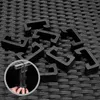 A close-up view of several black plastic clips scattered on a textured black surface, with a circular inset showing hands attaching two clips to a piece of furniture. Produktbild-Vorschau