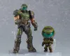 Two action figures of the Doom Slayer from the video game Doom Eternal are displayed against a plain background. One is a standard-sized Figma figure, and the other is a smaller, chibi-style Nendoroid figure. Náhľad obrázku produktu