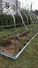 A partially assembled greenhouse frame on a grassy lawn. Produktbild-Vorschau