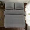 A top-down view of a neatly made bed with dark gray checkered bedding. Náhled obrázku produktu