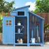 A blue wooden garden shed with various gardening tools and accessories stored inside and around it, set against a backdrop of greenery and a wooden fence. Voir les images du produit