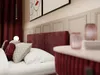 A close-up view of a bed with pillows and a bedside table. Produktbild-Vorschau