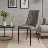 A dining chair is placed in a living room setting next to a coffee table with plants and a sofa in the background. Náhľad obrázku produktu