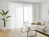 A bright and airy living room with a sofa, coffee table, and large sliding panel curtains. Produktbild-Vorschau