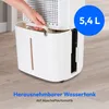 A person's hand is shown removing a water tank from a white dehumidifier. The dehumidifier is placed on a light wood-grain floor. Produktbild-Vorschau