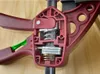 A close-up view of the internal mechanism of a red and green clamp, showing springs and metal components. Náhled obrázku produktu