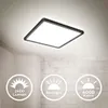 A square LED ceiling light is shown mounted on a white ceiling, with a brick wall in the background. Three circular icons with text are displayed in the lower left corner. Voir les images du produit