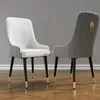 Two dining chairs are shown against a plain gray wall and a wooden floor. Voir les images du produit