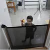 A young child is holding a toy while standing behind a baby gate in a home environment. Náhľad obrázku produktu
