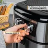 A hand is shown adjusting the temperature dial on an air fryer, with bread rolls in a basket in the background. Produktbild-Vorschau