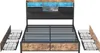 A bed frame with a headboard featuring LED lighting and storage compartments, shown with pull-out drawers beside it. Produktbild-Vorschau