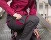 A person is kneeling on a metal grate, adjusting the pocket of their work pants. Anteprima dell’immagine prodotto