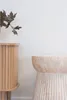 A close-up of a wooden cabinet and a stone side table against a white wall. Podgląd zdjęcia produktu