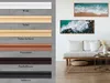 A display of different frame color options next to a living room scene with artwork on the wall. Produktbild-Vorschau