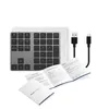 A gray numeric keypad with black keys, two black USB cables, and open instruction manuals are arranged on a white background. Náhled obrázku produktu