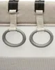 Close-up of two grey rings attached to beige fabric with black clips. Produktbild-Vorschau