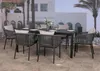 An outdoor dining set with chairs and a table, set against a backdrop of a building and palm trees. Anteprima dell’immagine prodotto