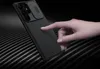 A hand is touching a black smartphone case with a textured surface and a sliding camera cover. Anteprima dell’immagine prodotto