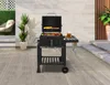 A charcoal grill with food cooking on it, placed on a wooden deck next to a patio chair and plants. Produktbild-Vorschau
