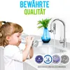 A young girl drinks water from a glass next to a kitchen sink with a faucet and a decorative vase. Produktbild-Vorschau