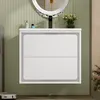 A modern white bathroom vanity with two drawers, mounted on a wall with green ribbed paneling. A round mirror with an ornate frame is above the vanity. A faucet and a vase of flowers are also visible. Produktbild-Vorschau