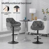 Two dark gray bar stools are shown in a modern living room setting with a small round table and a white cabinet in the background. The image highlights features like adjustable height and 360-degree swivel. Náhľad obrázku produktu