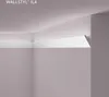 A corner of a room showing a white decorative molding strip installed at the junction of a wall and ceiling, designed for indirect lighting. Produktbild-Vorschau