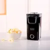 A black Black+Decker popcorn maker sits on a white surface next to a bowl of popcorn. Produktbild-Vorschau