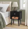 A bedroom scene featuring a black nightstand next to a bed. Produktbild-Vorschau