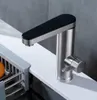 A modern kitchen faucet with a black top and silver body, positioned on a white countertop next to a sink rack. Produktbild-Vorschau