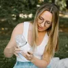 A woman is holding a portable bottle warmer outdoors. Produktbild-Vorschau