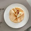 A dessert or pastry is presented on a white plate, garnished with a dried lemon slice and white chocolate. Náhled obrázku produktu
