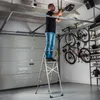 A man is standing on a stepladder in a garage, working on a garage door opener. Náhľad obrázku produktu