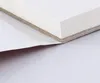 A close-up view of the edge of a white paper block, showing layers of paper and a greyish backing material, with a white sheet peeling away from the bottom. Podgląd zdjęcia produktu